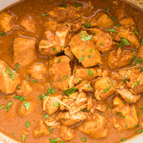 butter chicken cubes in a slow cooker with cilantro.