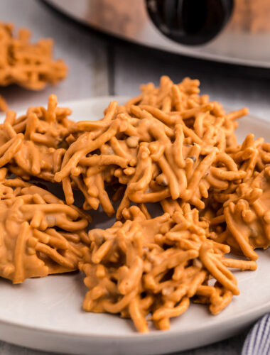 butterscotch haystacks on a plate in front of a crockpot.