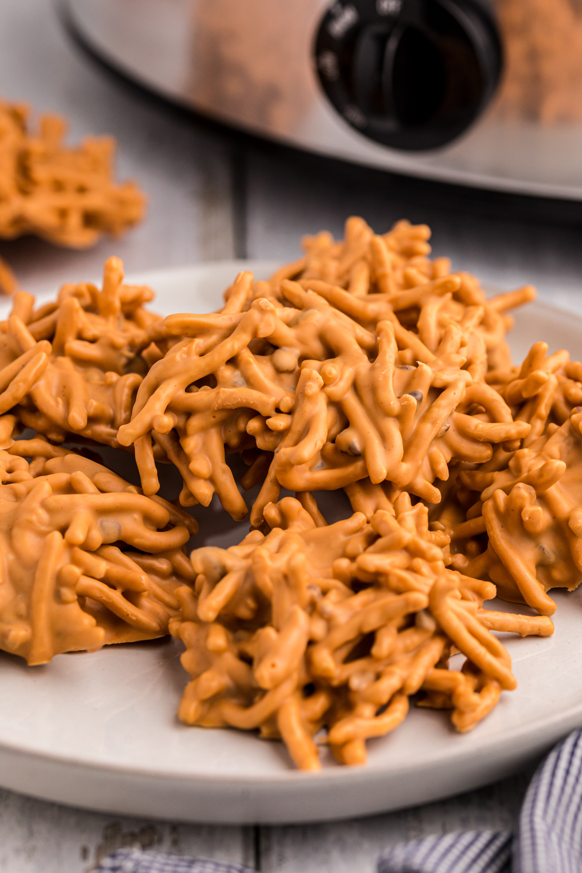 butterscotch haystacks on a plate in front of a crockpot.