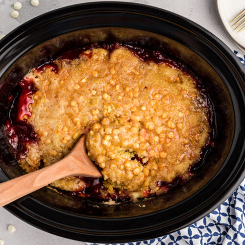 cherry dump cake in a slow cooker with a spoon in it.