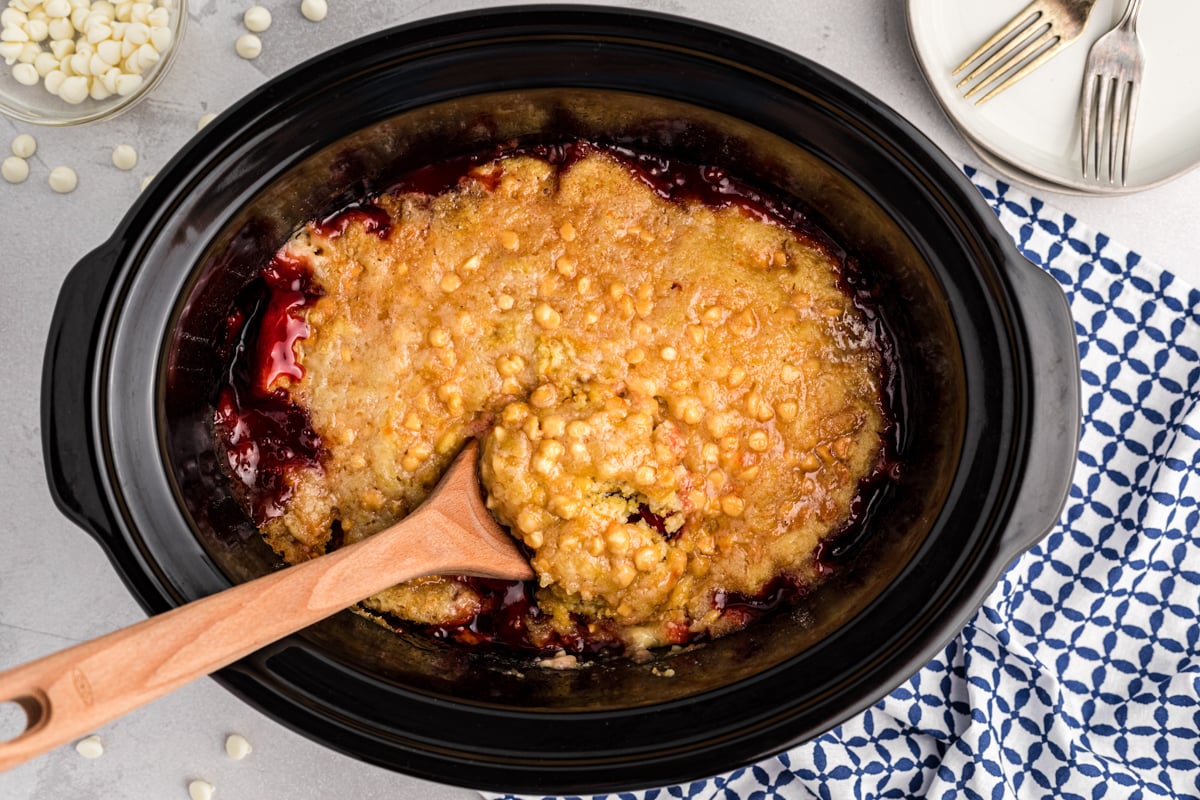 cherry dump cake in a slow cooker with a spoon in it.
