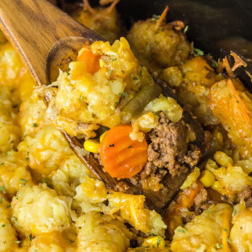 close up of shepherd's pie tater tot casserole on a wooden spoon in a crockpot.