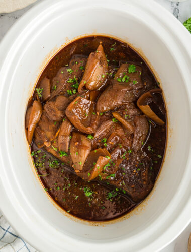 Beef brisket with onions and barbecue sauce in a slow cooker.