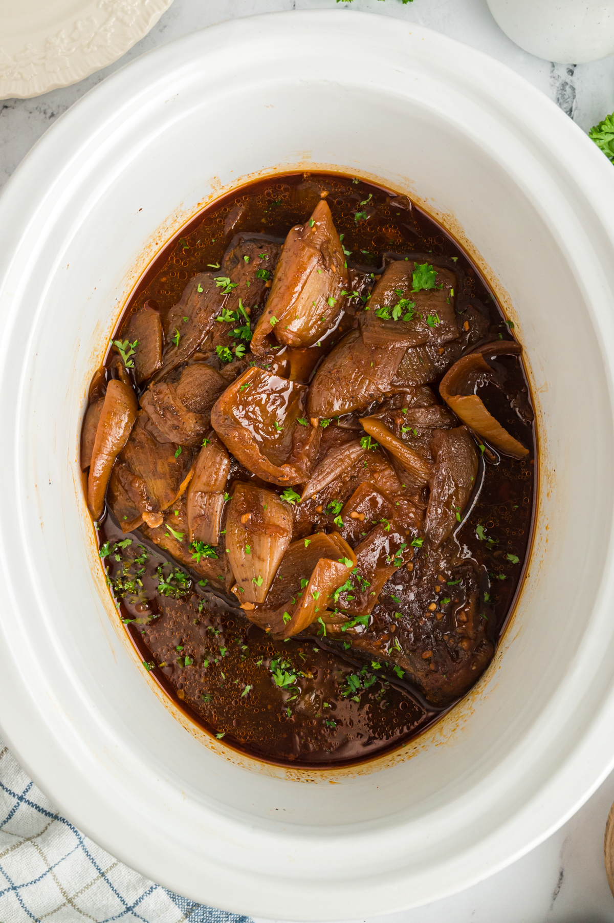 Beef brisket with onions and barbecue sauce in a slow cooker.