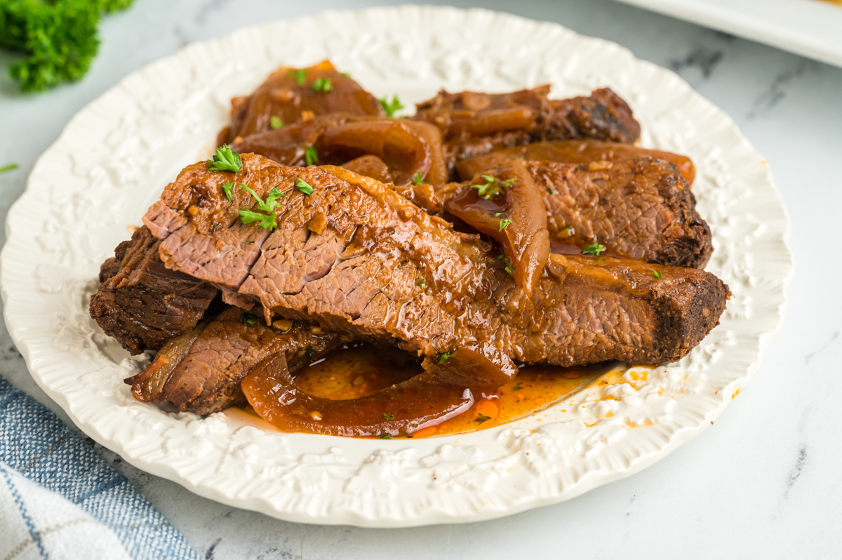 Pile of beef brisket on a white plate.
