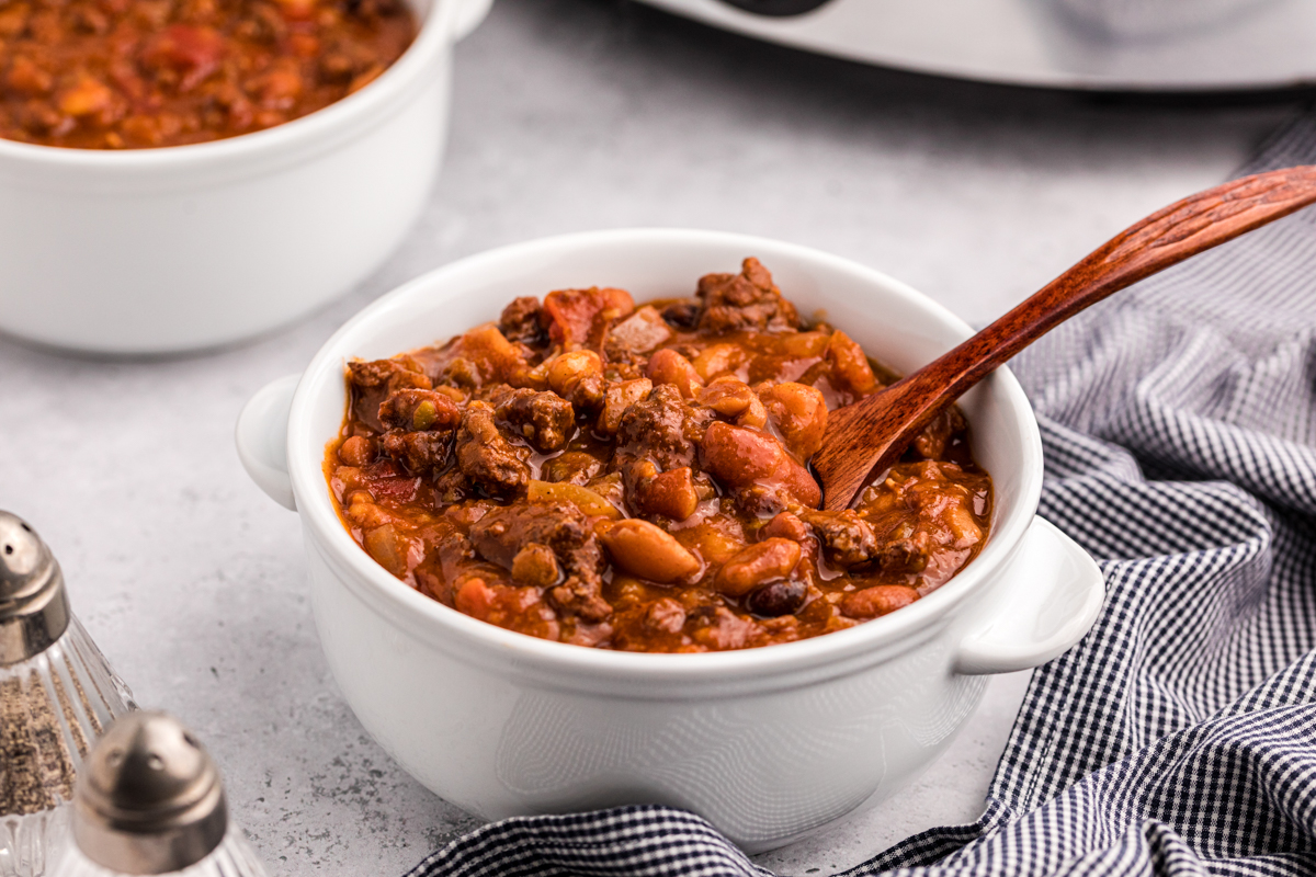 Bowl of 15 bean chili with a wooden spoon in it.