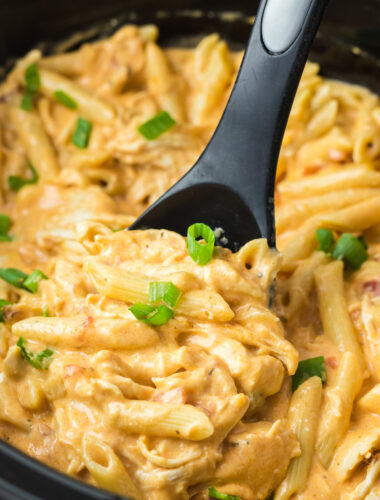 close up of buffalo chicken pasta in a slow cooker with a spoon in it.