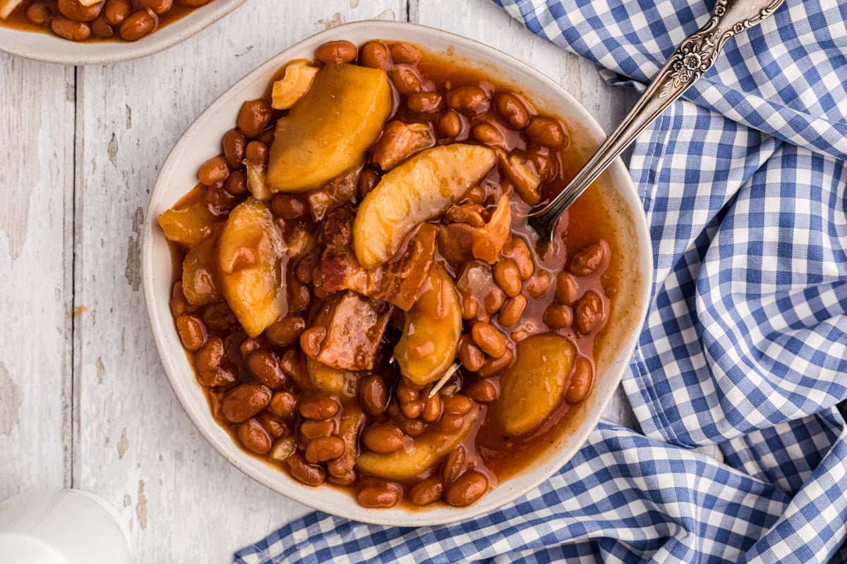 Plate full of baked beans with apples.