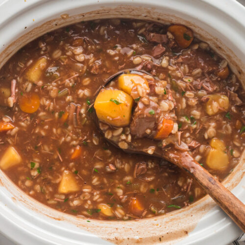 beef barley soup in a white slow cooker, done cooking.
