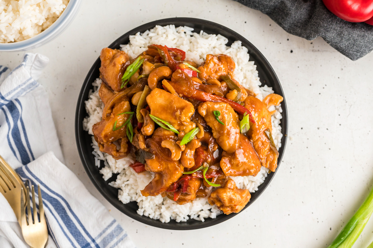 Plate of cashew chicken over rice with forks on the side.
