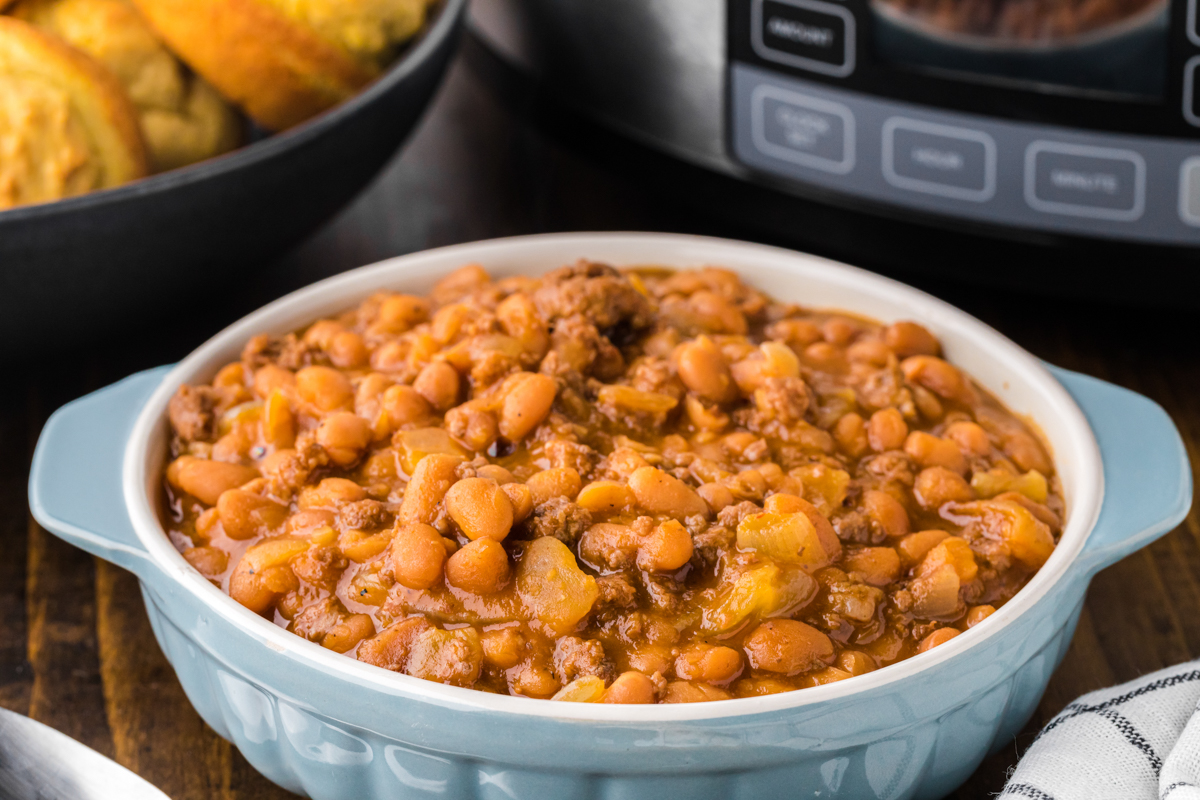 Bowl of cowboy beans in front of a crockpot.