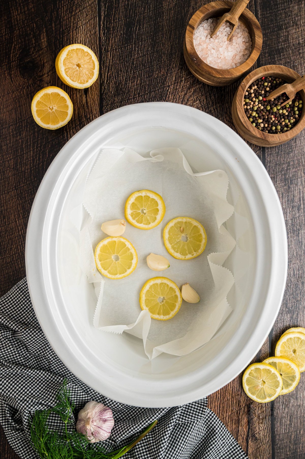 lemons and butter in the bottom of a white slow cooker.