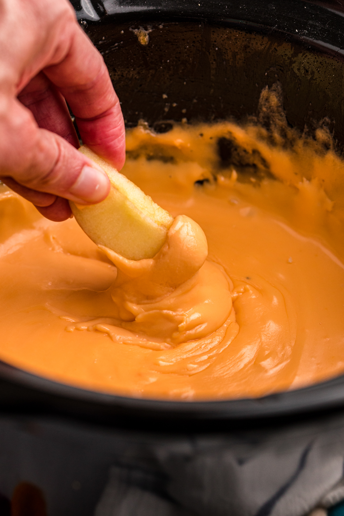 apple being dipped into cheese fondue.