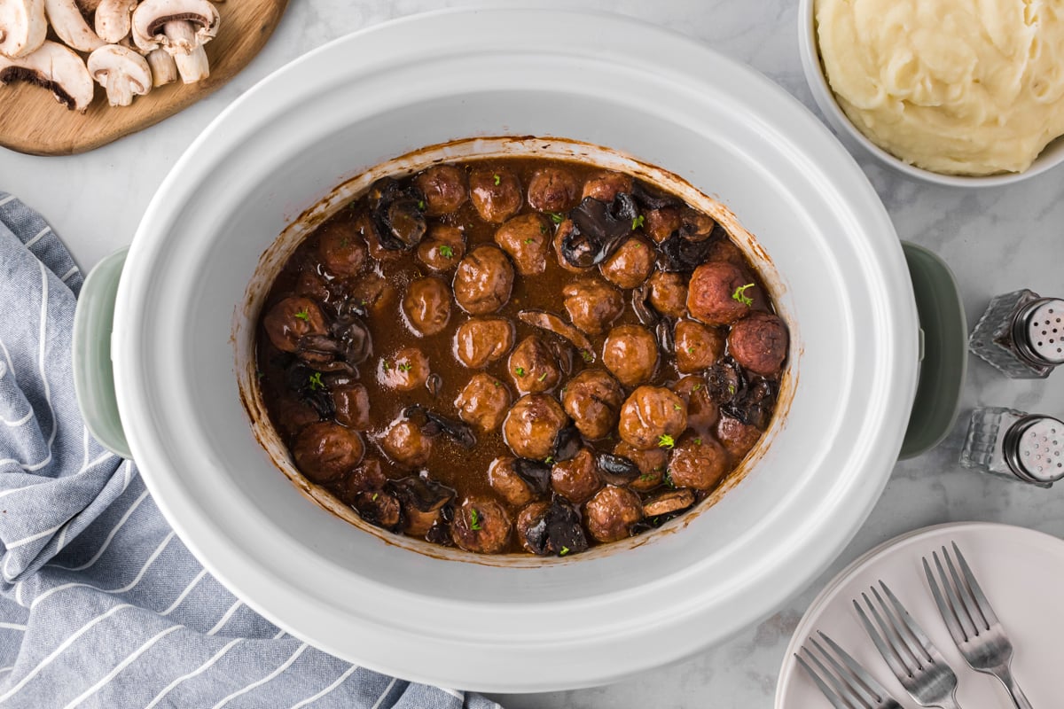 meatballs in a slow cooker with brown gravy.