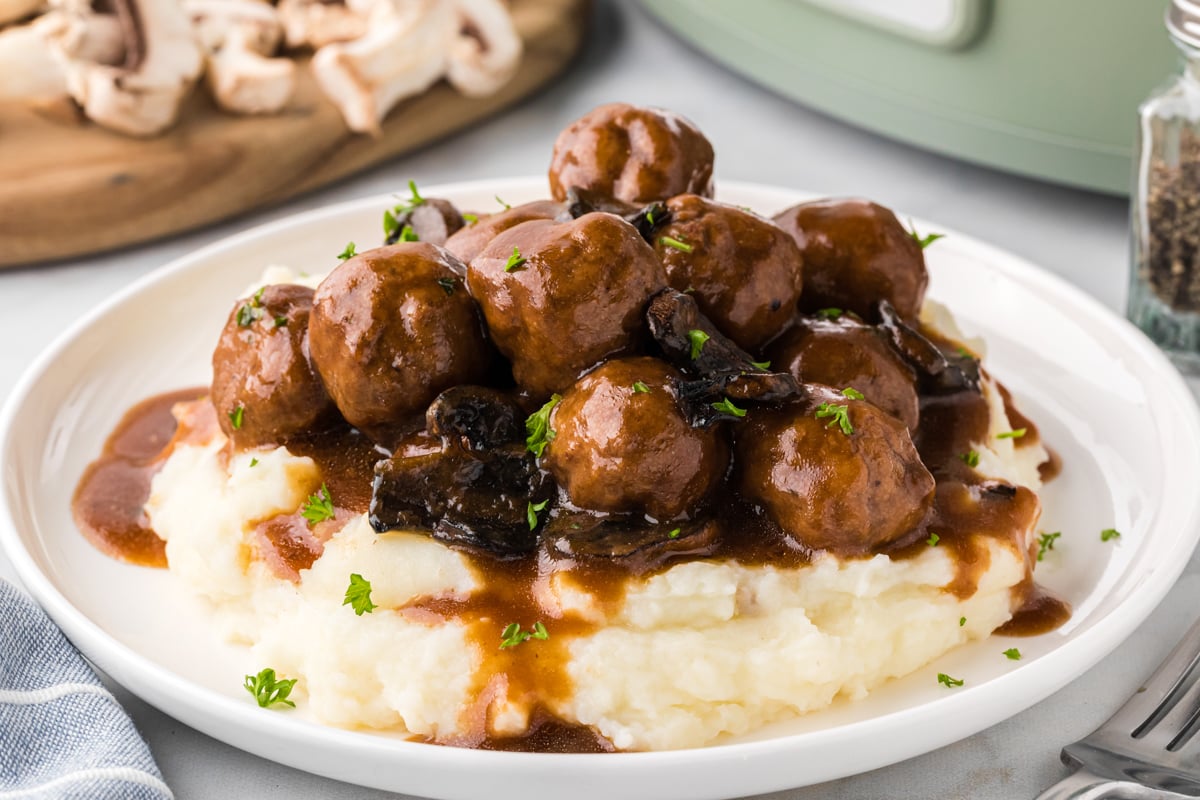 plate of meatballs with gravy over mashed potatoes.