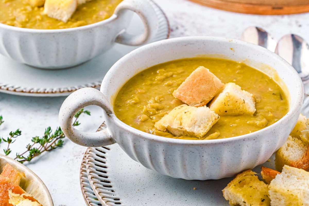 bowl of split pea soup with croutons on top.

