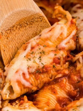 Close up of stuffed shells with a wooden spoon.