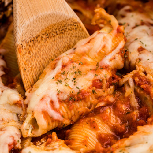 Close up of stuffed shells with a wooden spoon.