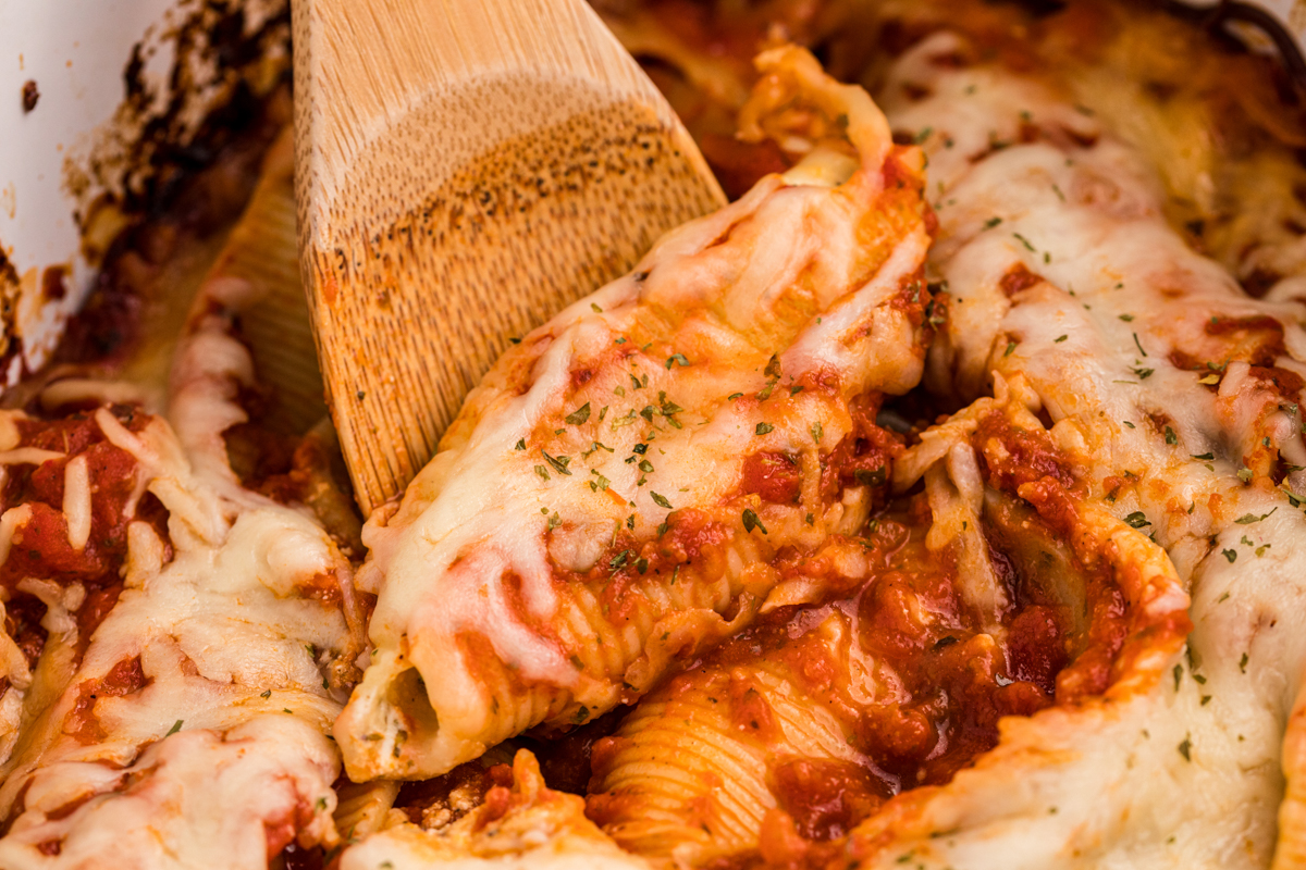 Close up of stuffed shells with a wooden spoon.