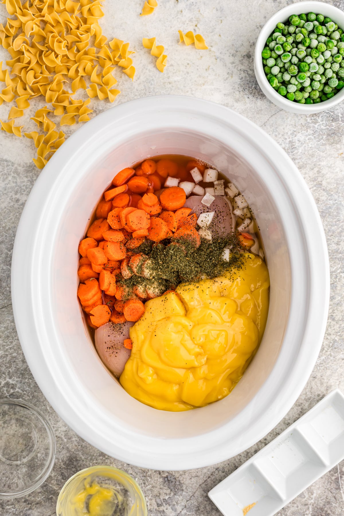 Chicken, vegetables, seasonings and cream of chicken soup in a slow cooker.