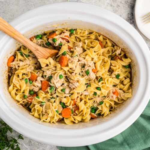 noodles and chicken with peas and carrots in a slow cooker.