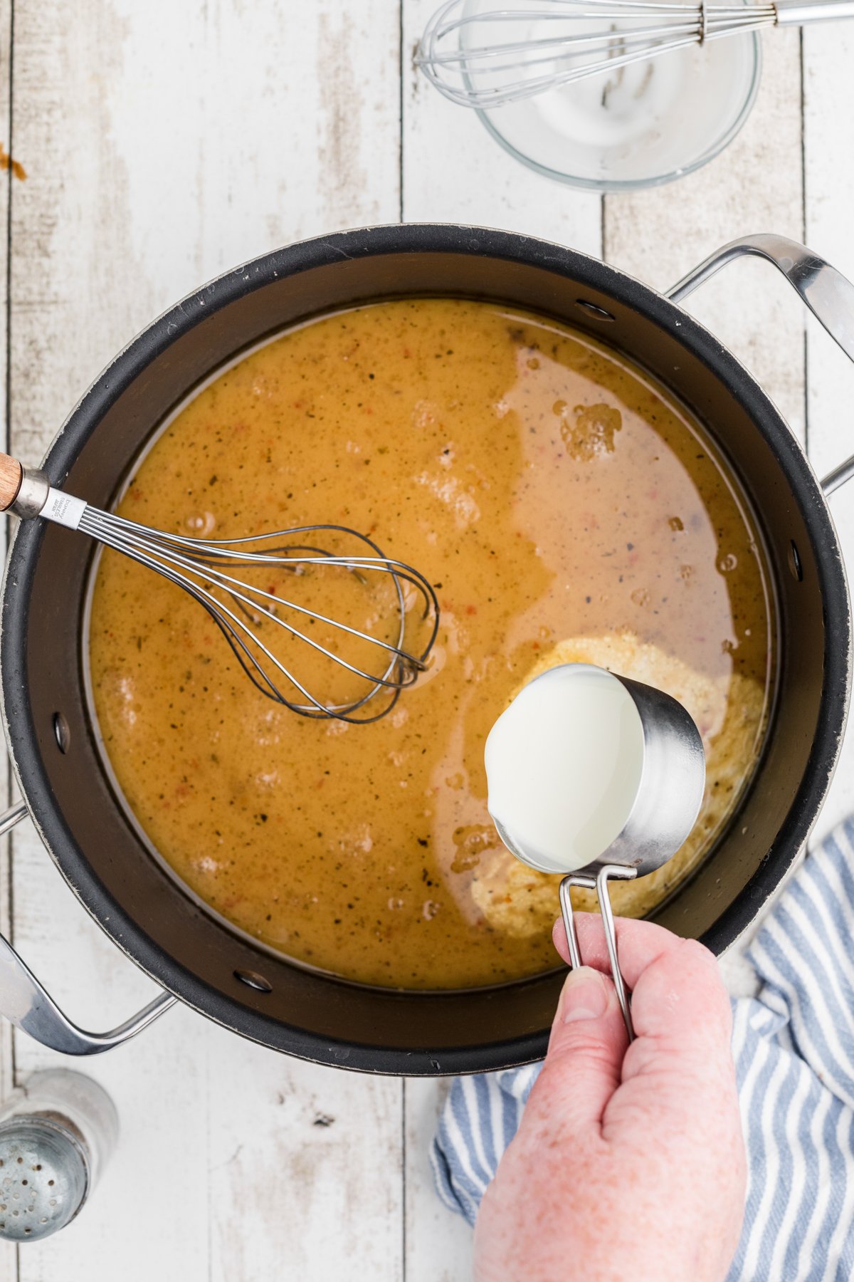 cornstarch slurry being added to drippings in a pan.