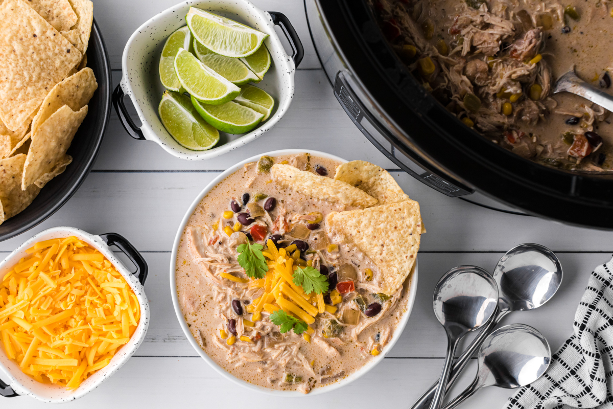 overhead shot of chicken fajita soup, chips, cheese and limes.