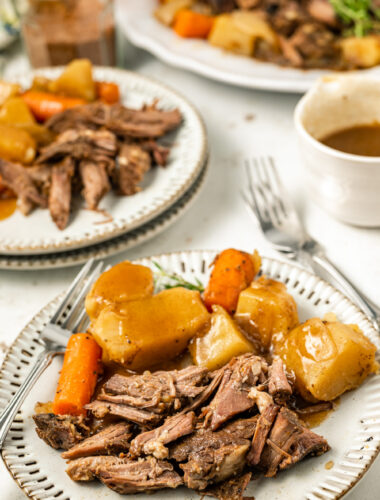 coffee pot roast on a plate with gravy and vegetables.