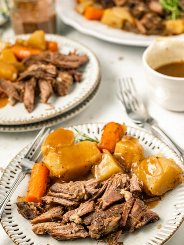 coffee pot roast on a plate with gravy and vegetables.