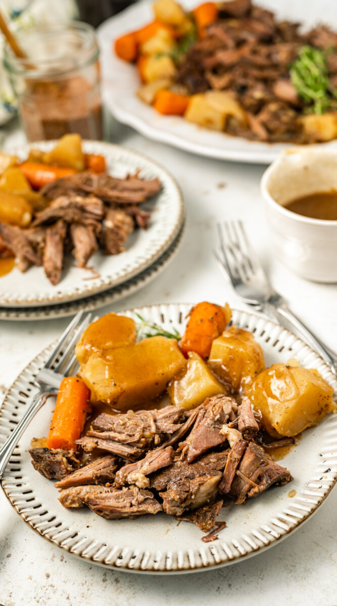 coffee pot roast on a plate with gravy and vegetables.