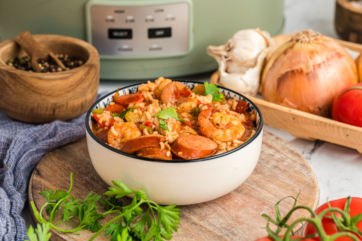 Bowl of crockpot jambalaya in front of a slow cooker.