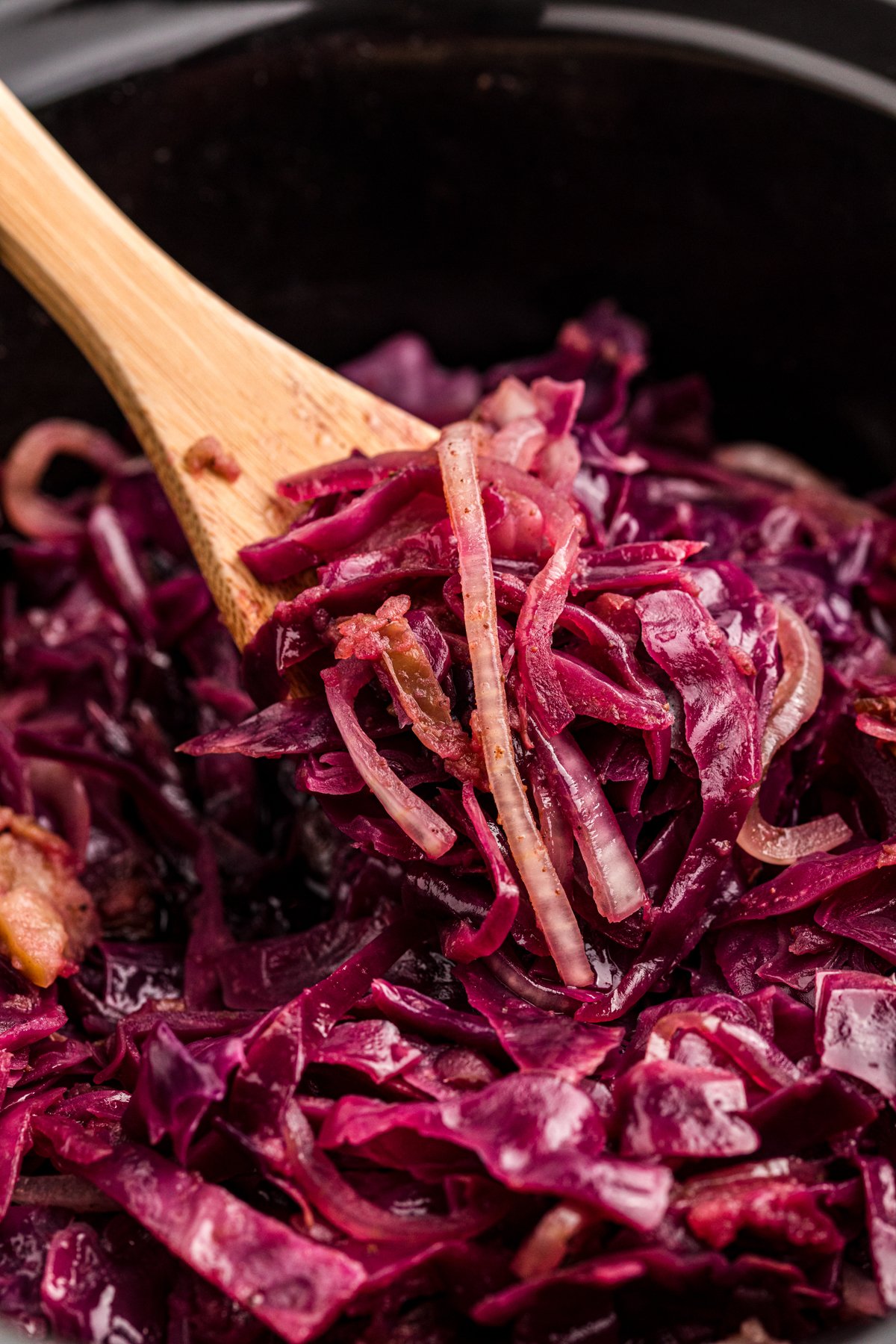 Red cabbage on a wooden spoon in a slow cooker.