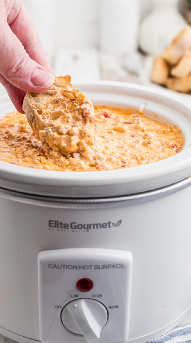 Long image of a piece of bread being dipped into pimento cheese.