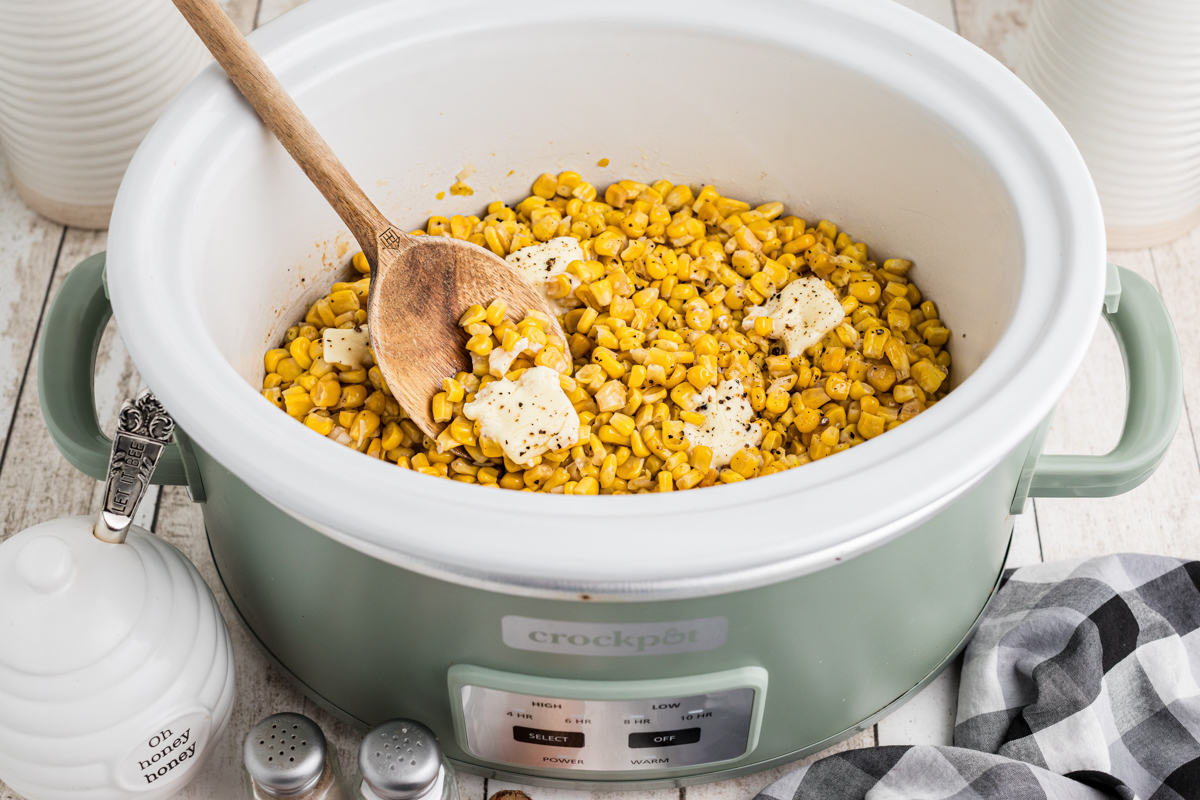cooked corn with butter on top in a slow cooker.