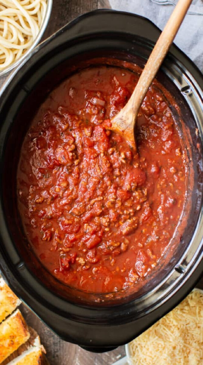 long image of spaghetti sauce with a wooden spoon in it.