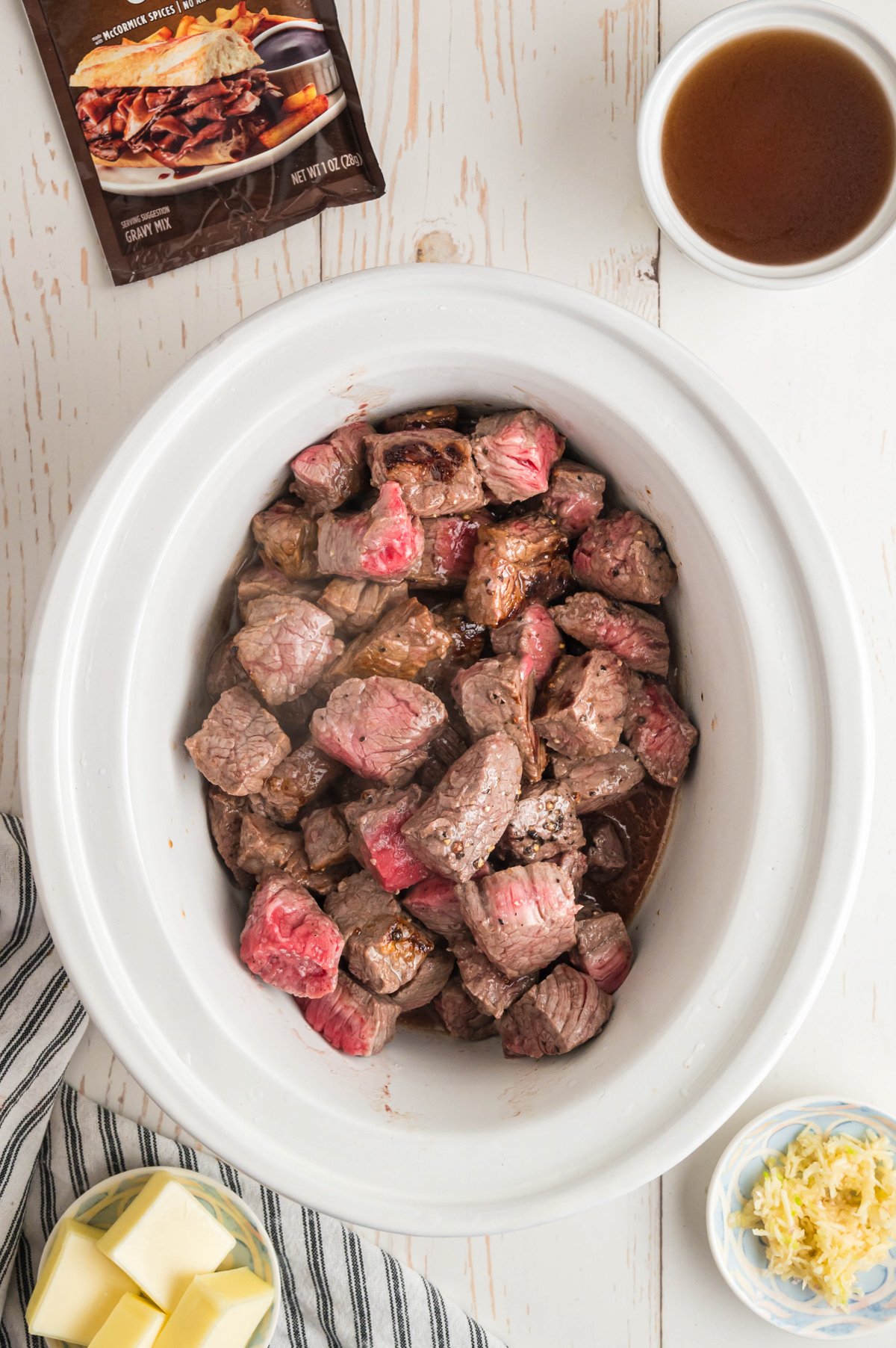 cubed steak in a white slow cooker.