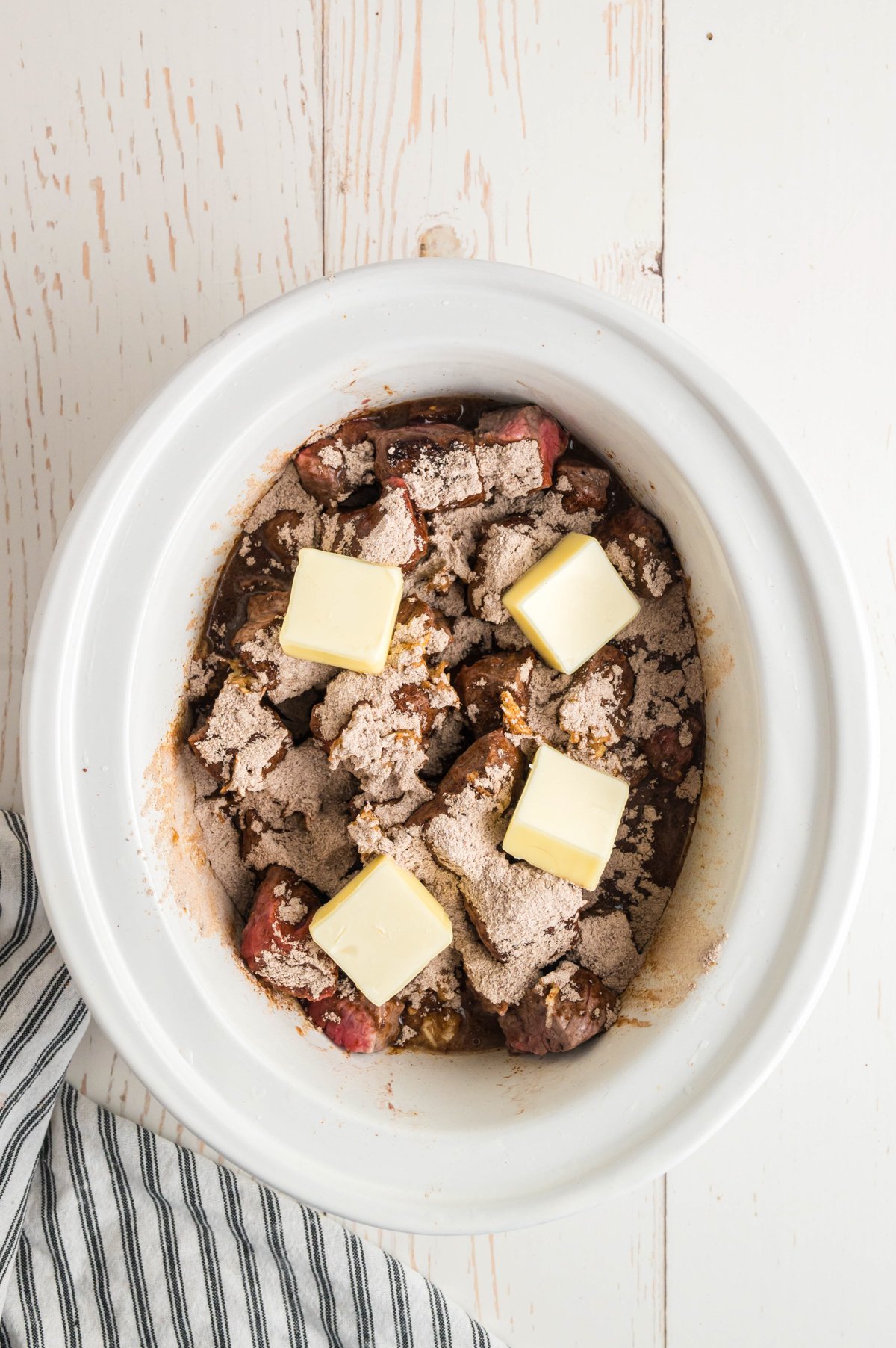 butter and au jus on top of the browned steak in the slow cooker.