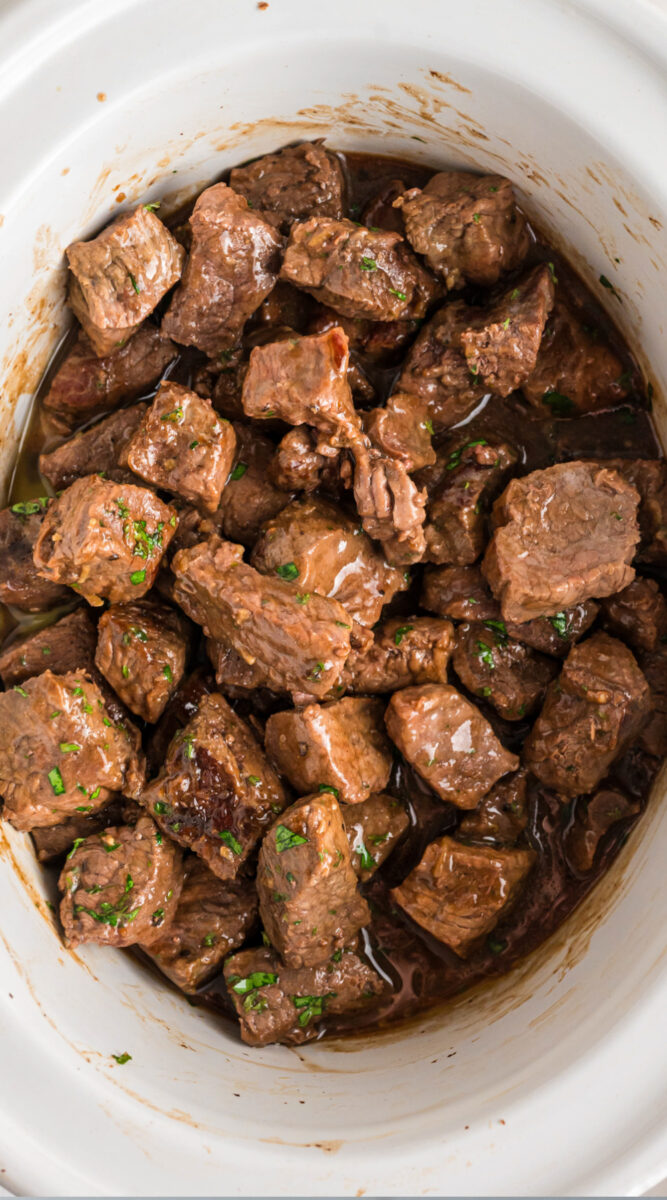 Long image of steak bites in a slow cooker.