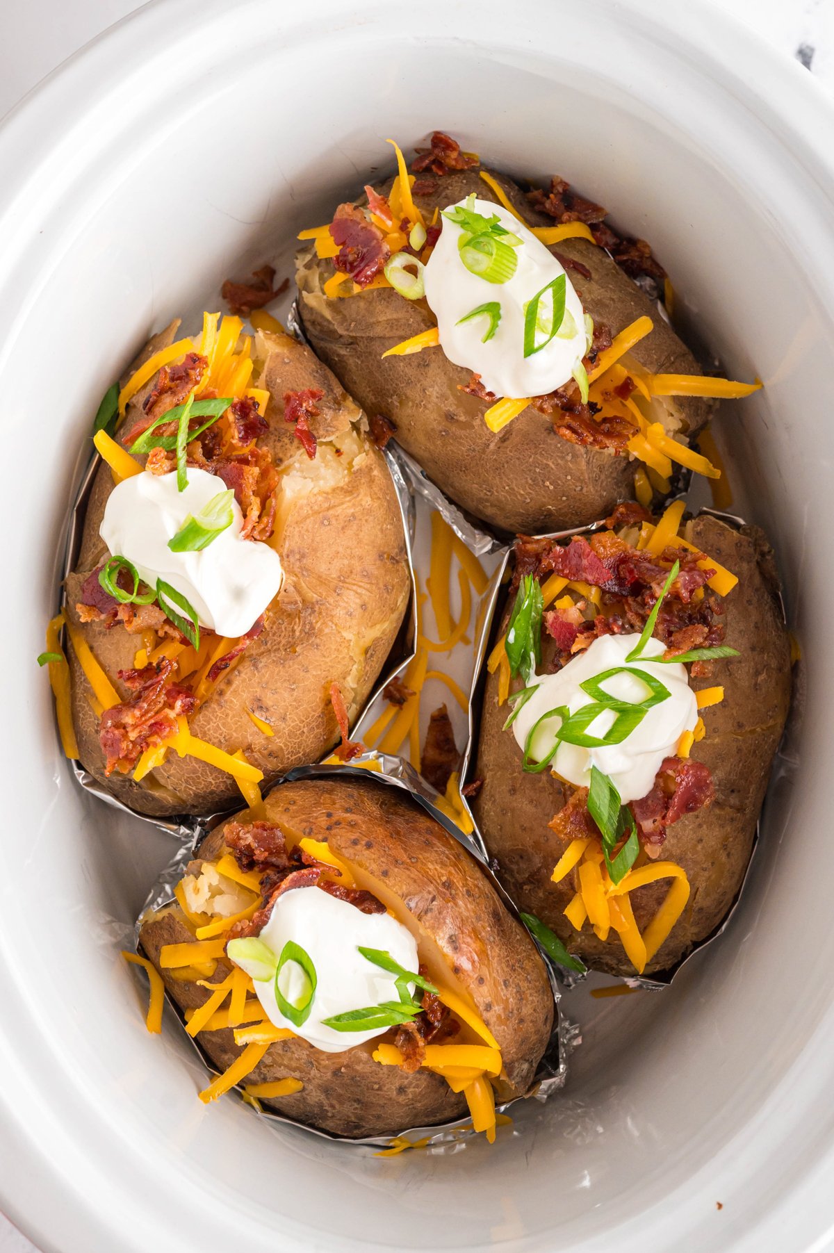 Cooked loaded baked potatoes in a crockpot.