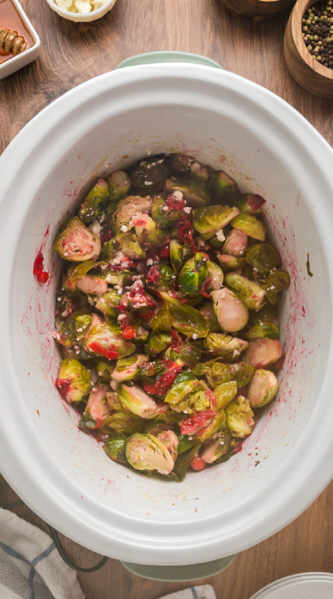 Long image of brussels sprouts with cranberries in a slow cooker.
