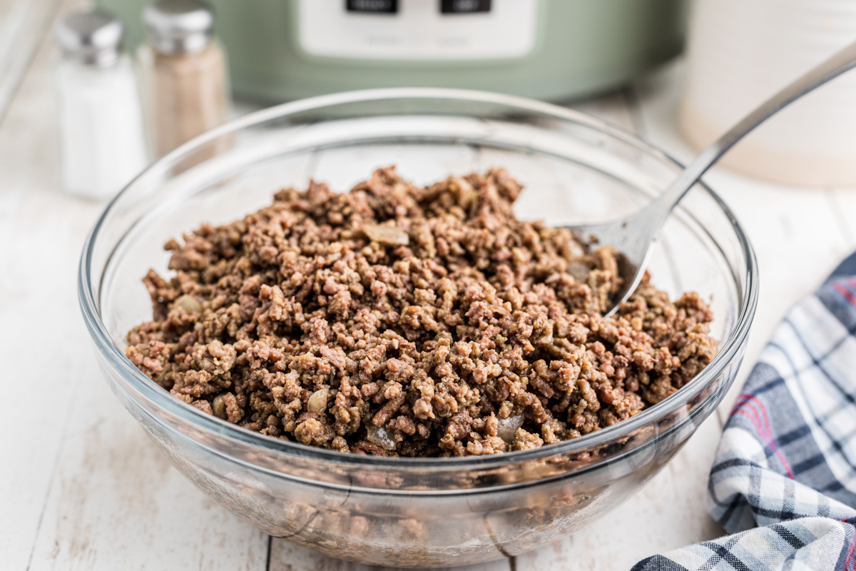 Bowl of ground beef with a spoon in it.