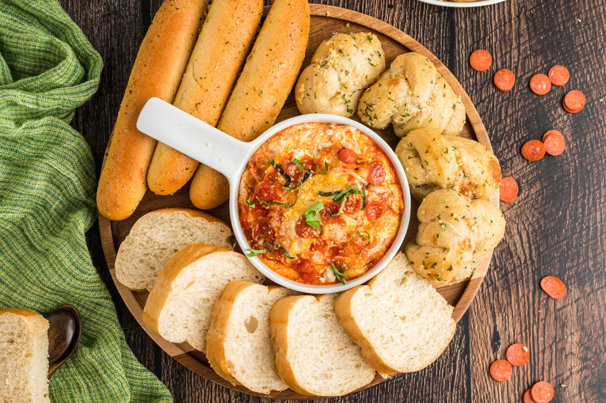 overhead shot of pizza dip in a bowl with 3 kinds of bread.