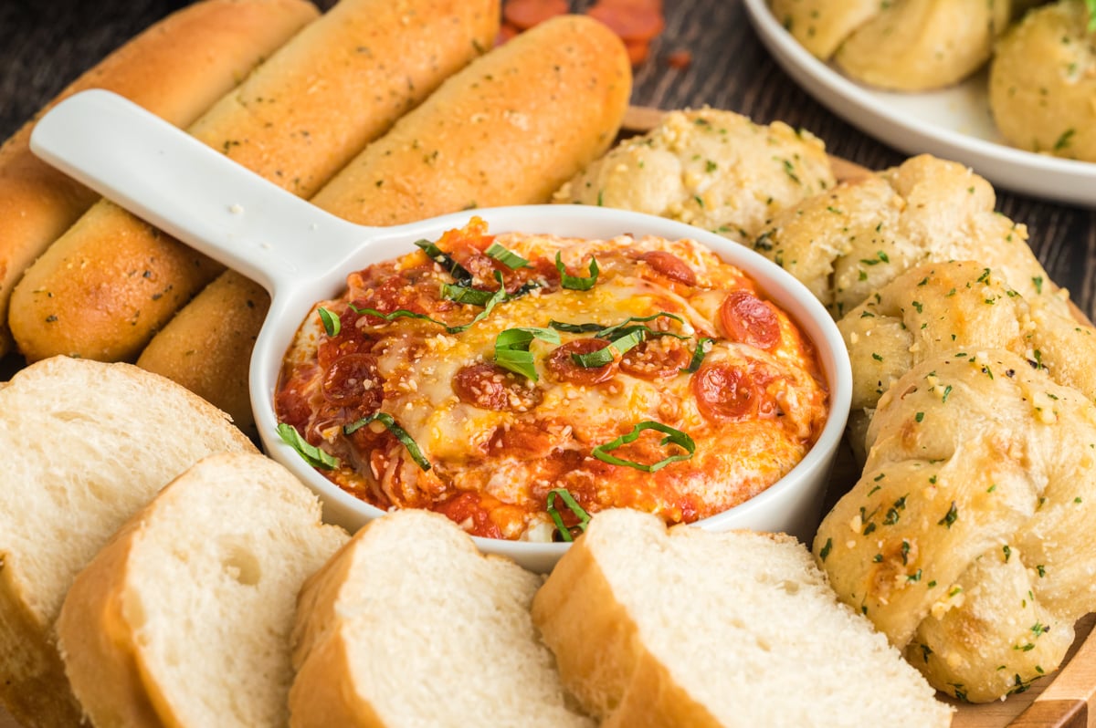 pizza dip in a bowl with bread around the sides.