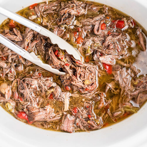 Cooked and shredded italian beef in a slow cooker.