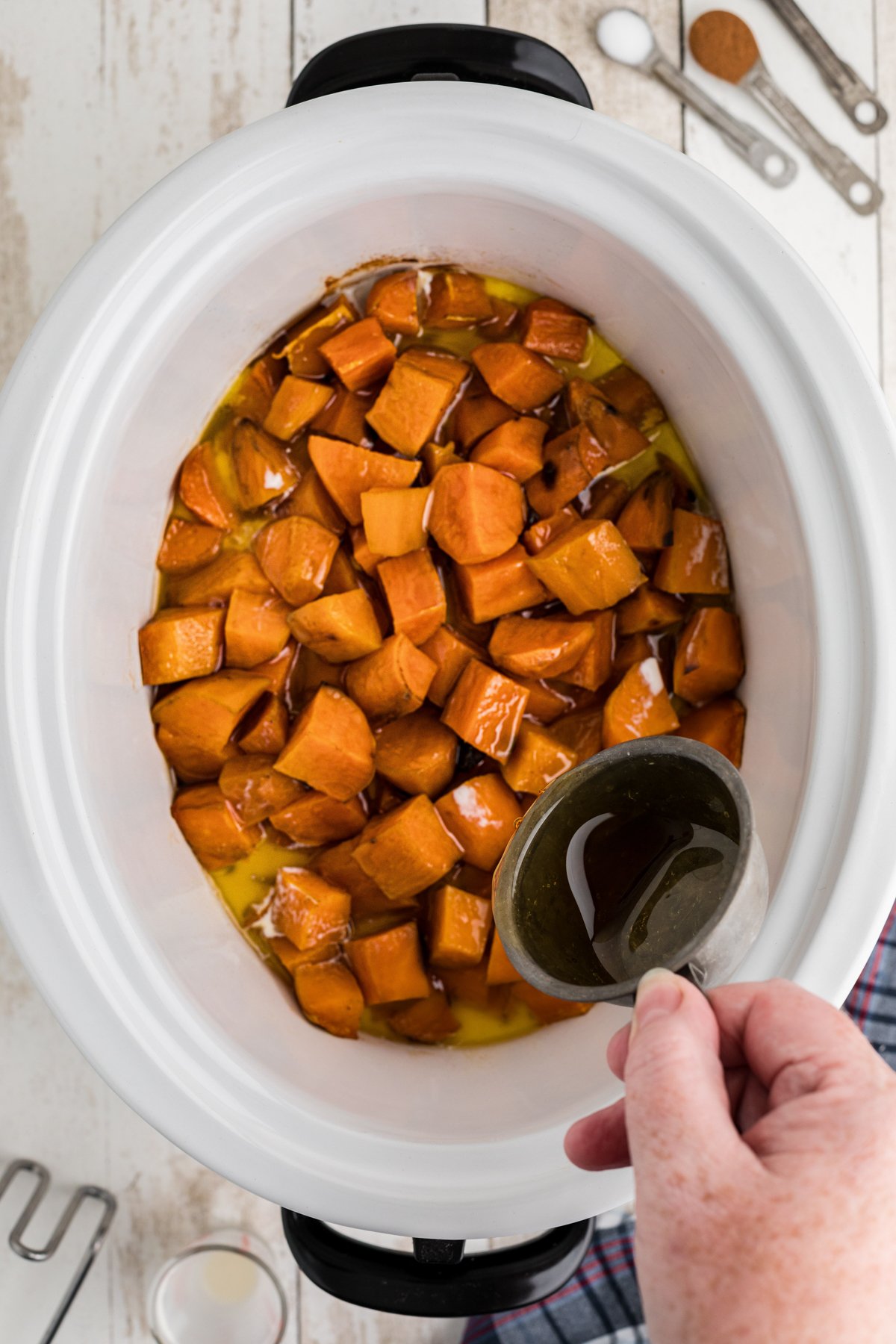 maple syrup being pour over cooked sweet potatoes.