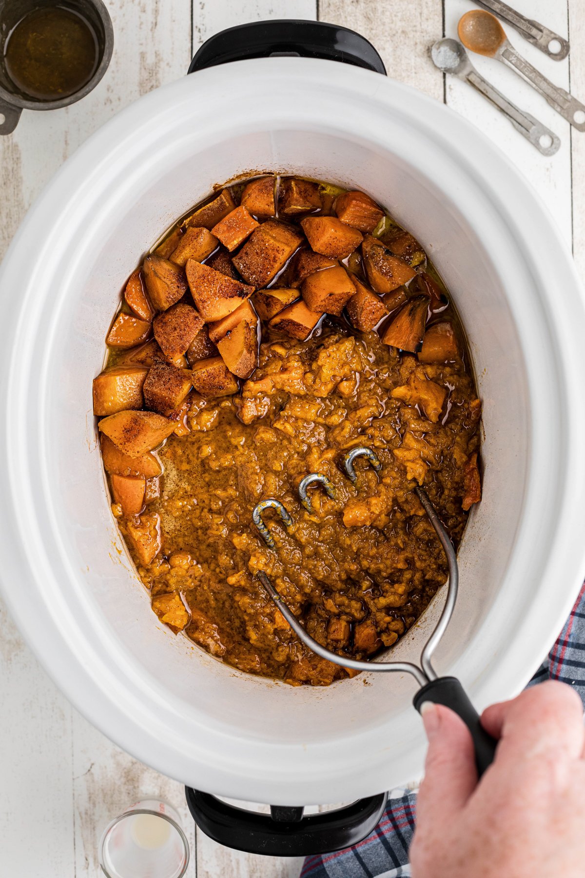 sweet potatoes being mashed in the crockpot.