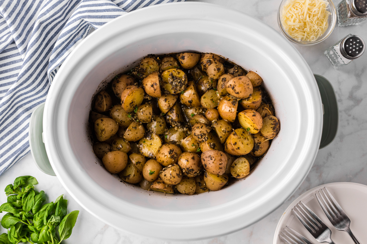 Overhead shot of pesto parmesan potatoes in a slow cooker.