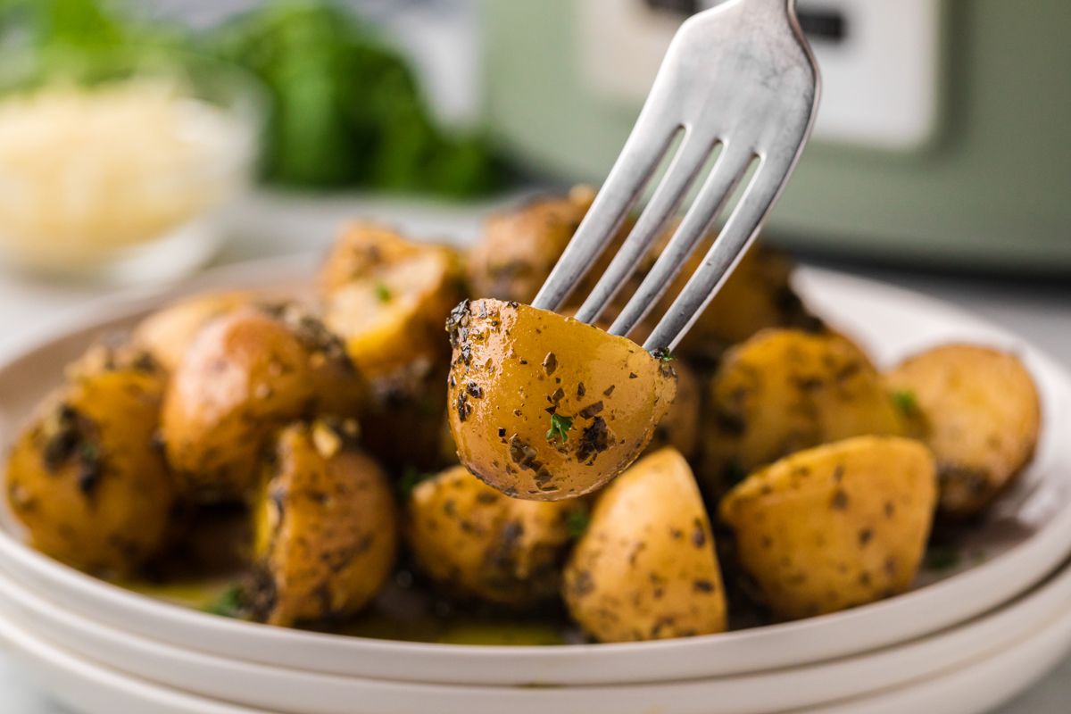 Close up of baby potatoes on a plate with a fork in one.