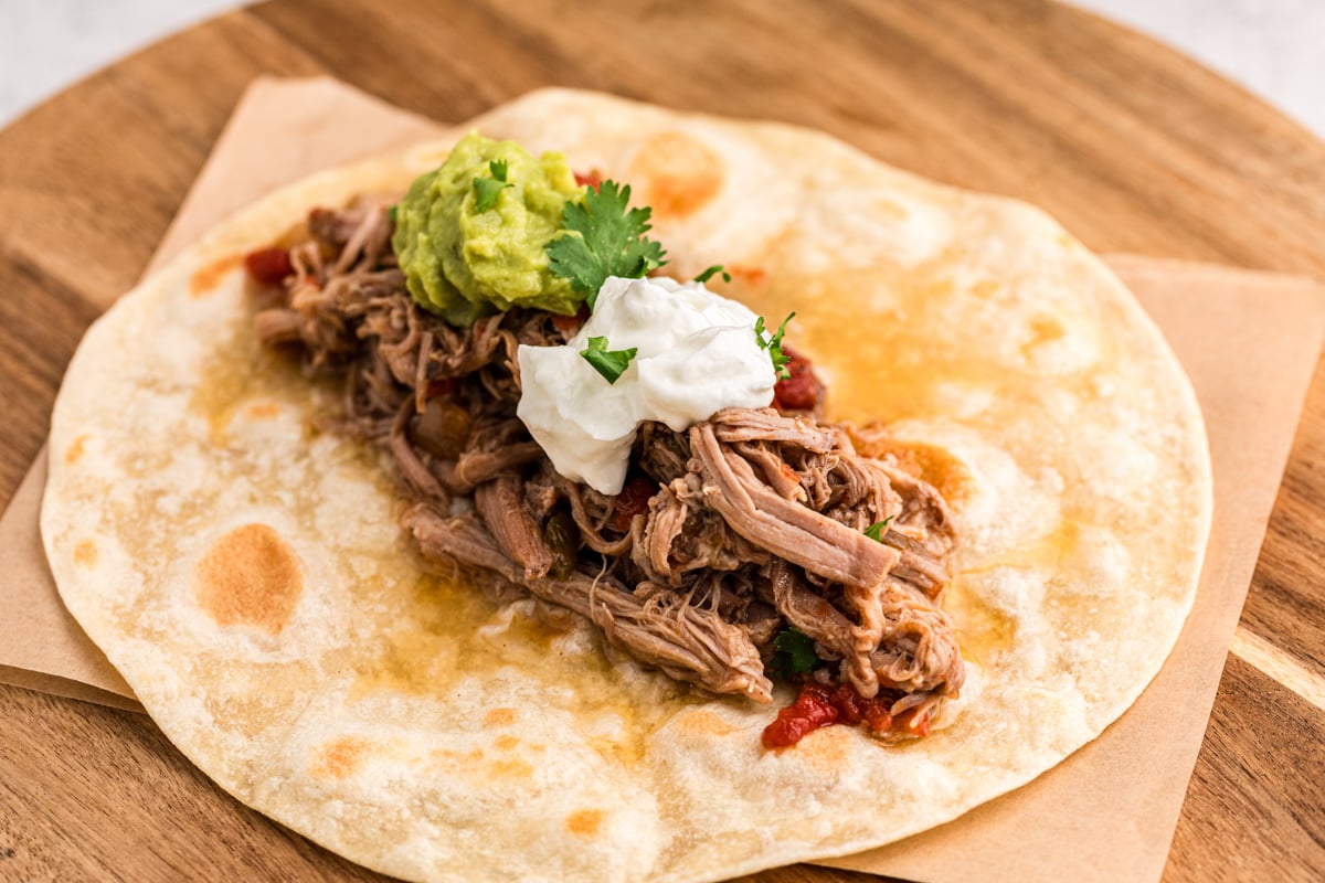 shredded pork on a tortilla with sour cream and guacamole.
