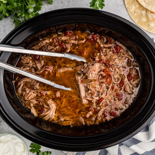 overhead shot of shredded pork burrito filling in a slow cooker.